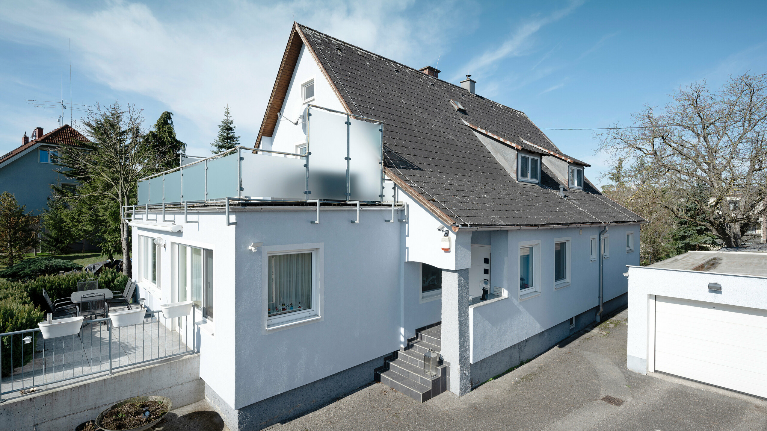 Das Bild zeigt das alte, verwitterte Dach eines Einfamilienhauses in Leonding aus einer seitlichen Perspektive, bevor die Sanierung und der Austausch der Eternitplatten gegen moderne PREFA Solardachplatten durchgeführt wurde. Sichtbare Abnutzungen und Schäden des Eternit-Daches verdeutlichen die Notwendigkeit einer Erneuerung. Diese Aufnahme dokumentiert den Zustand des Daches vor der Umwandlung in eine nachhaltige und energieeffiziente Dachlösung aus Aluminium. 