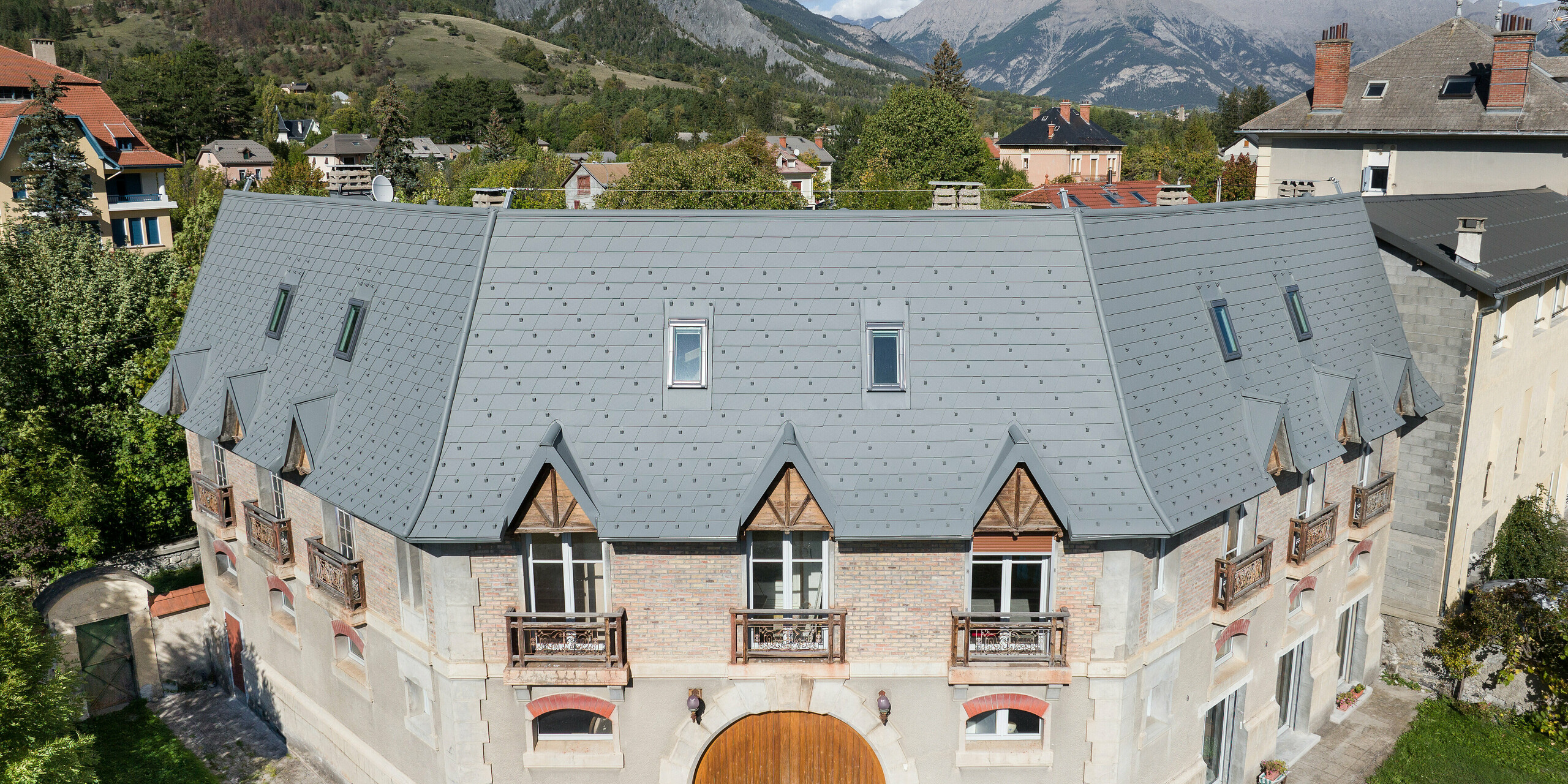 Pogled s sprednje strani na posestvo v kraju Barcelonnette v Franciji. Velika strešna površina je bila sanirana s strešnimi skodlami PREFA v P.10 svetlo sivi barvi. 