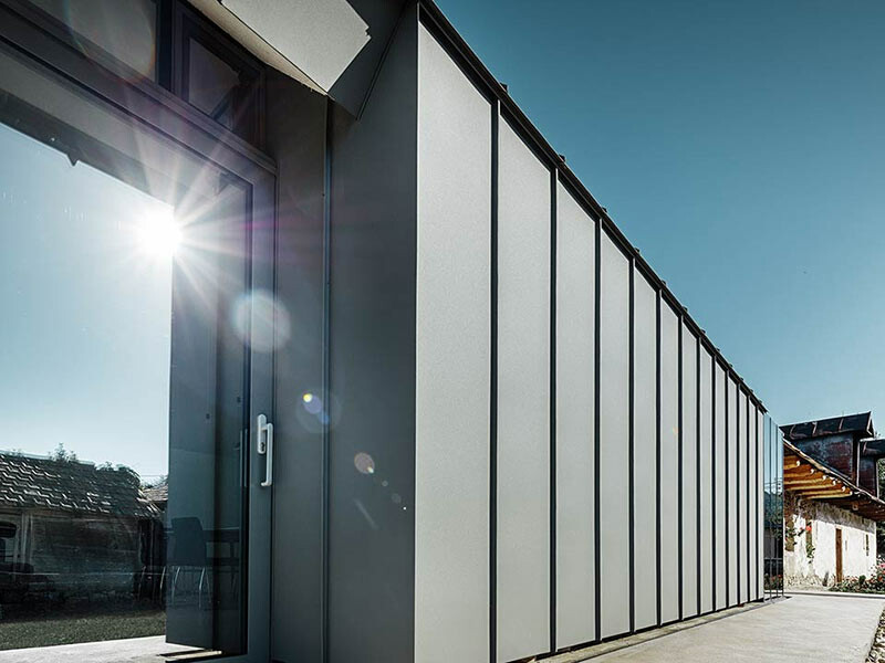 Winkelstehfalzfassade aus Aluminium von PREFA in Hellgrau mit großer Fensterfläche;