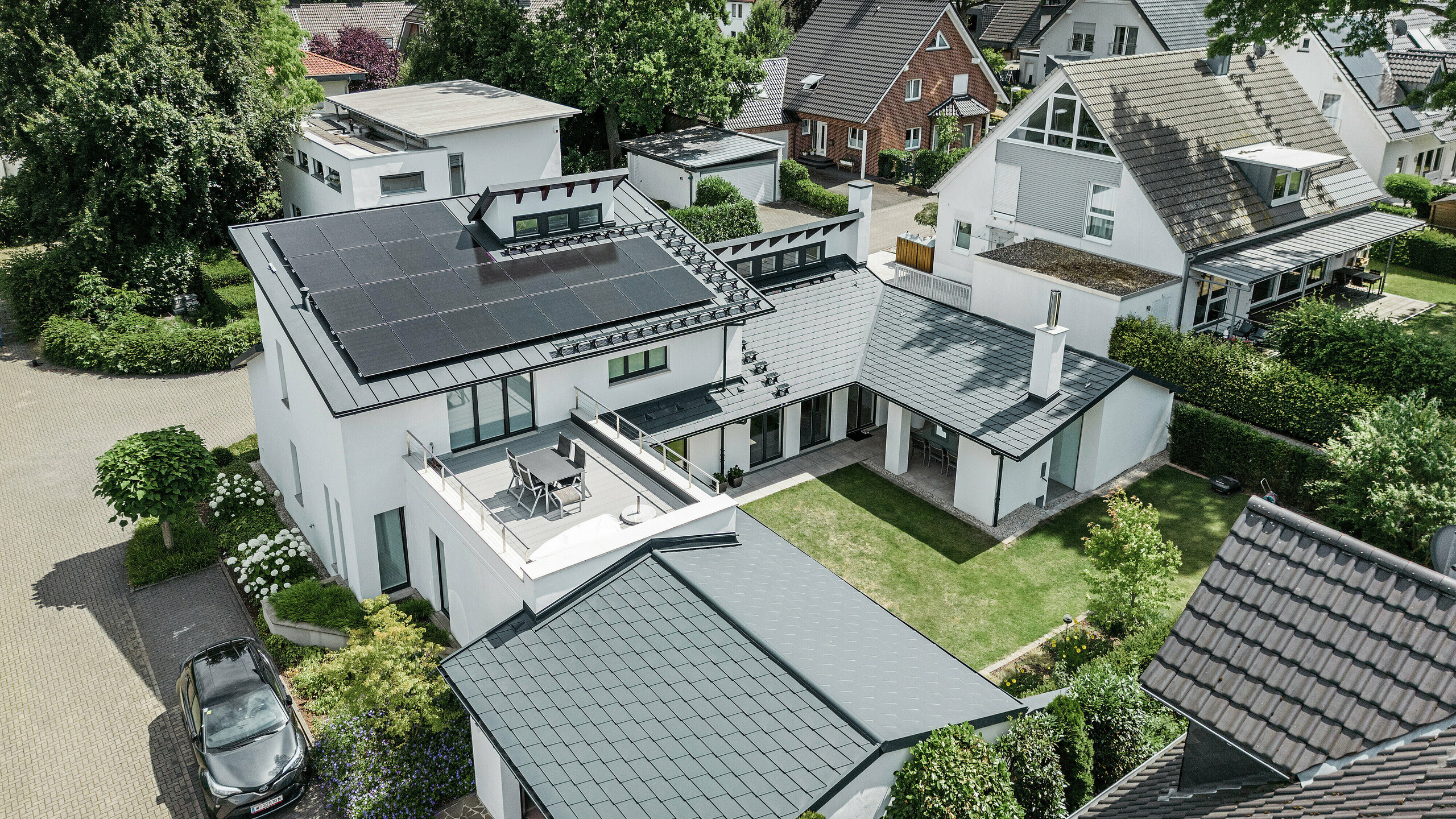 Pogled s ptičje perspektive na izjemno strešno pokrajino samostojne hiše v Dortmundu s strešniki PREFA DS.19 in PREFALZ v antracitni barvi P.10 ter obsežnim fotovoltaičnim sistemom